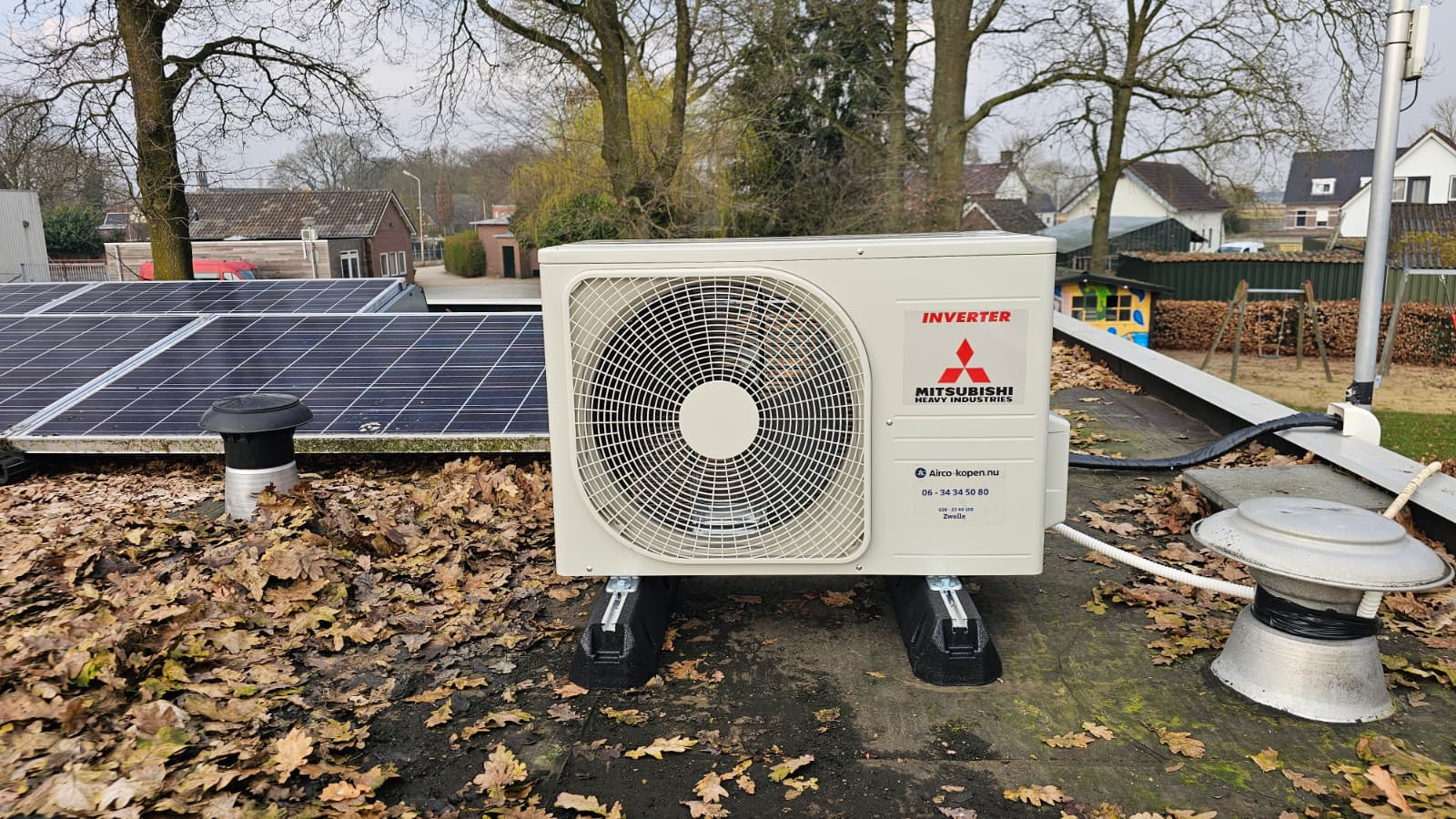 Buitenunit Mitsubishi Heavy Industries airco op plat dak naast zonnepanelen bij Zwembad Onder Ons in De Krim