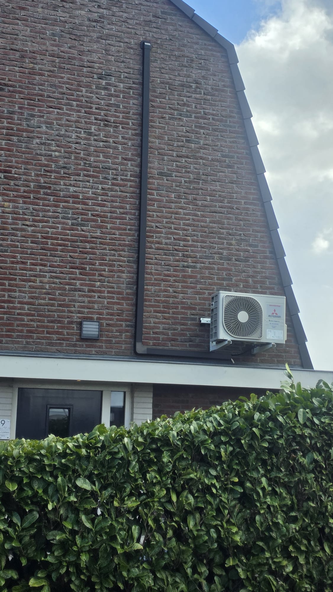 Mitsubishi Heavy Industries buitenunit aan gevel met zwarte leidinggoot in Tjalleberd