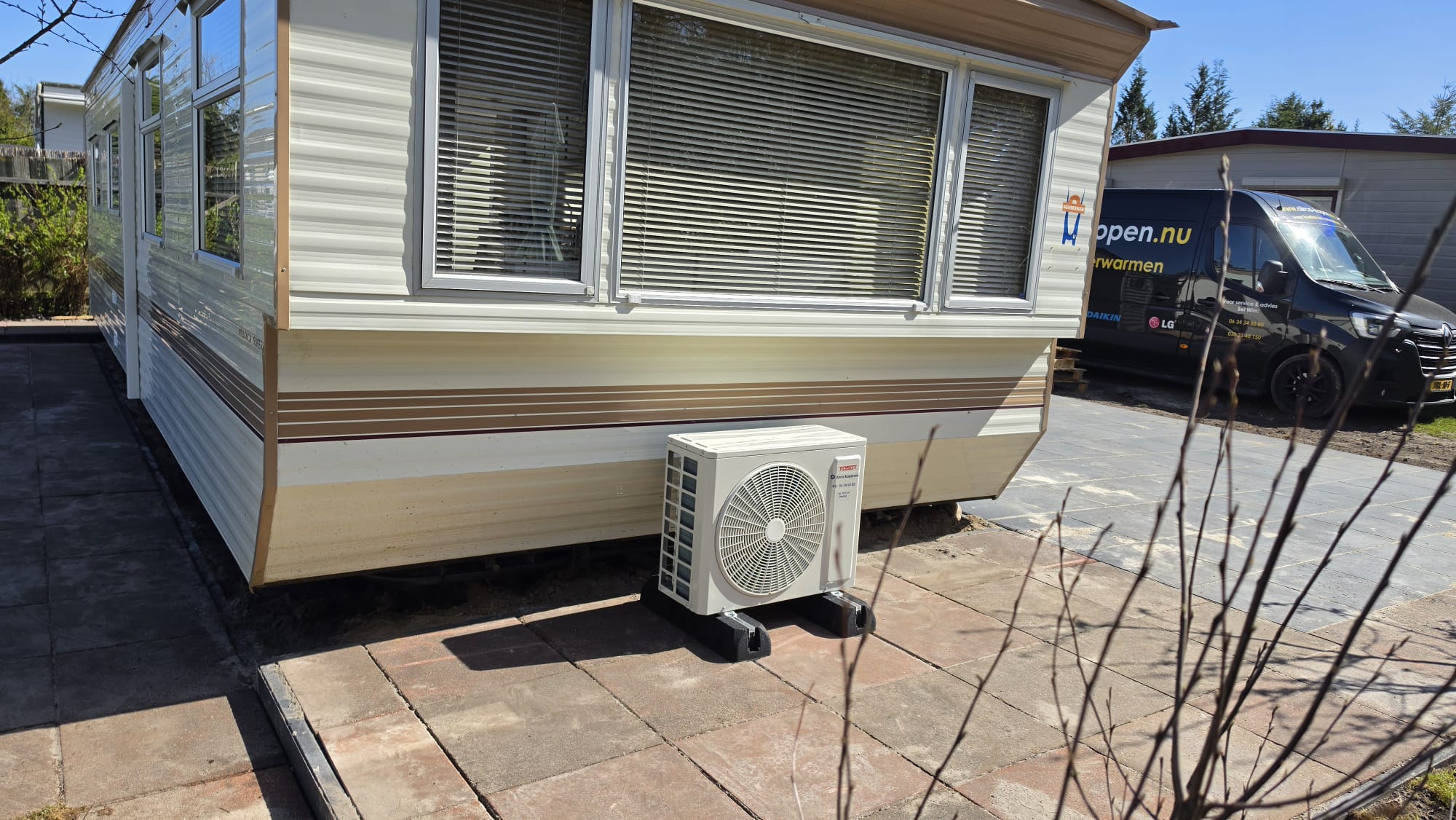 Buitenunit van Tosot Clivia Black 2,5 kW bij chalet op camping in Vierhouten
