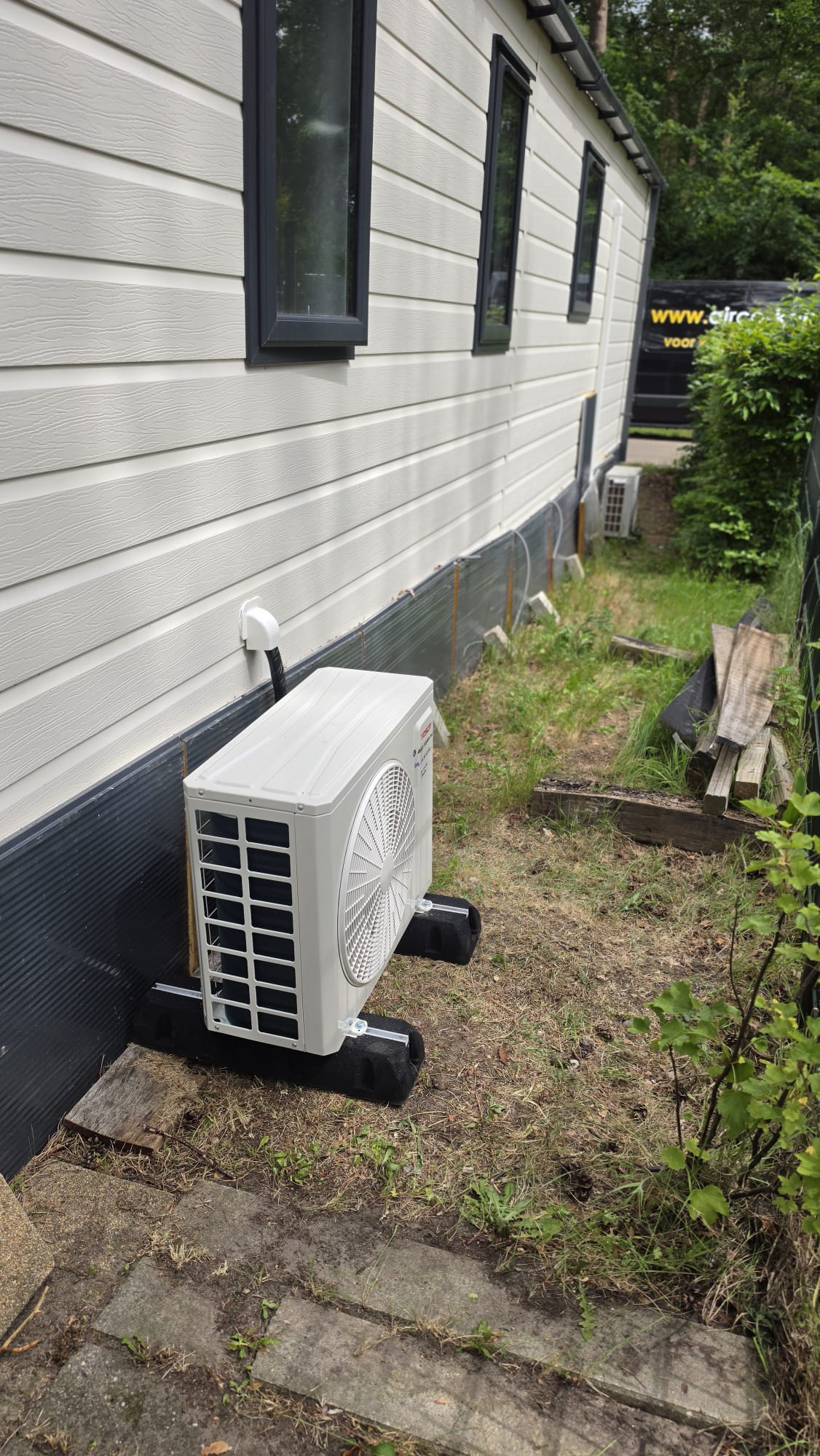 Buitenunit van Tosot CLIVIA airco naast chalet op Camping Samoza in Vierhouten geplaatst op rubberen geluiddempende blokken