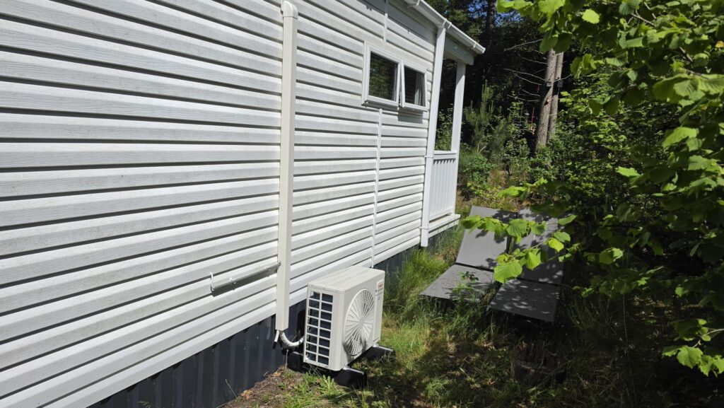 Tosot CLIVIA by GREE buitenunit naast wit chalet op Camping Ommerland in Ommen geplaatst op rubberen geluiddempende blokken