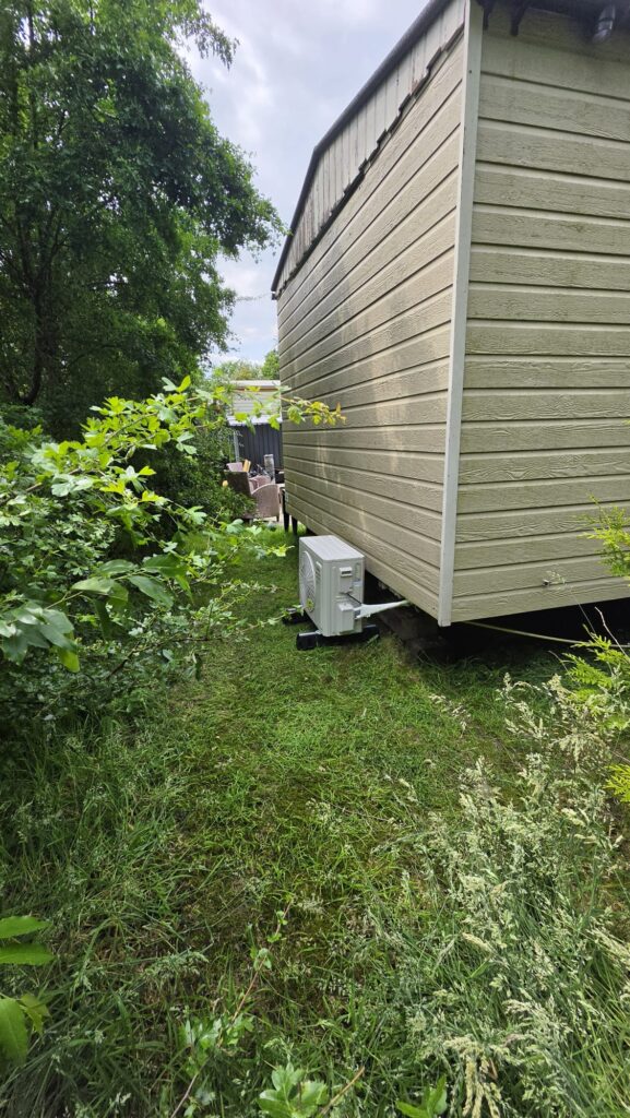 Tosot buitenunit achter chalet op Camping de Bosrand in Laren Gelderland op trillingdempende rubberen blokken