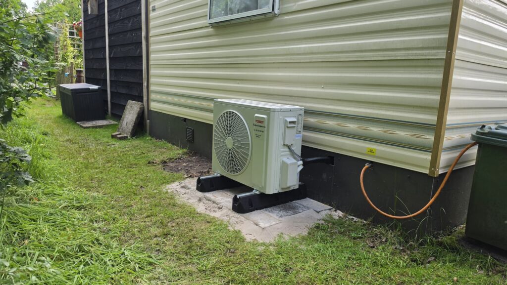 Buitenunit van Tosot CLIVIA 2,5 kW airco achter chalet op Camping de Bosrand in Laren Gelderland