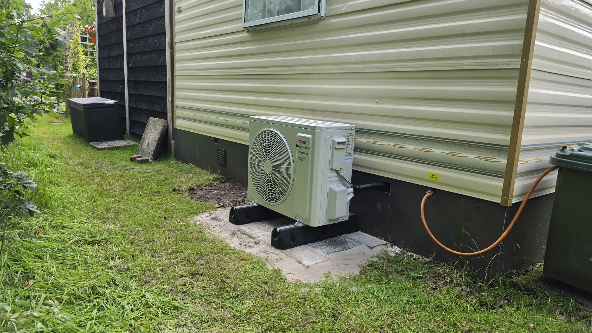Buitenunit van Tosot CLIVIA 2,5 kW airco achter chalet op Camping de Bosrand in Laren Gelderland